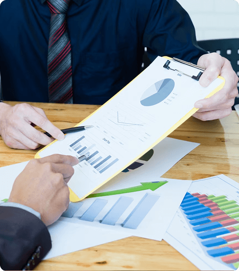 Two people reviewing business reports and graphs on clipboard