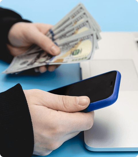 Hand accepting USD cash next to mobile phone