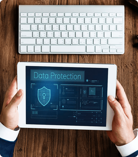 Tablet flat on desk showing a data protection UI next to a keyboard